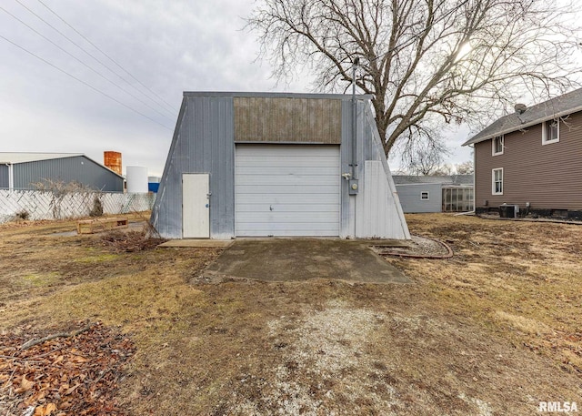 detached garage with driveway, fence, and central AC