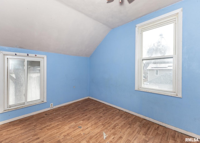 bonus room featuring vaulted ceiling, plenty of natural light, wood finished floors, and baseboards