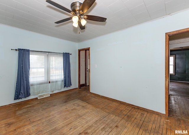 spare room featuring plenty of natural light, visible vents, ceiling fan, and hardwood / wood-style floors