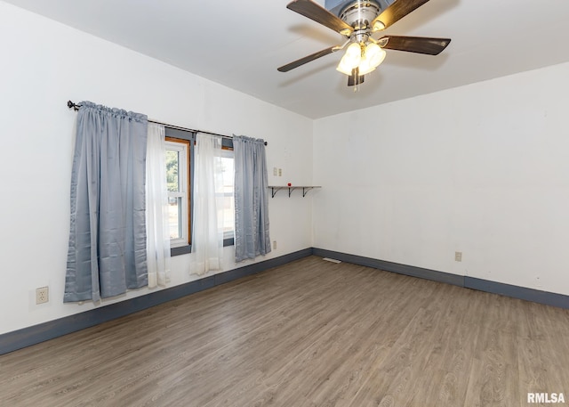 unfurnished room featuring wood finished floors, a ceiling fan, and baseboards