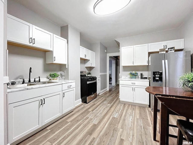 kitchen featuring sink, white cabinetry, stainless steel appliances, and light hardwood / wood-style flooring