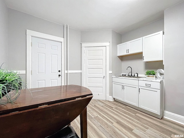 kitchen with white cabinets, light wood-type flooring, and sink