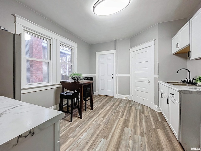 kitchen with white cabinets, sink, stainless steel refrigerator, and light hardwood / wood-style flooring