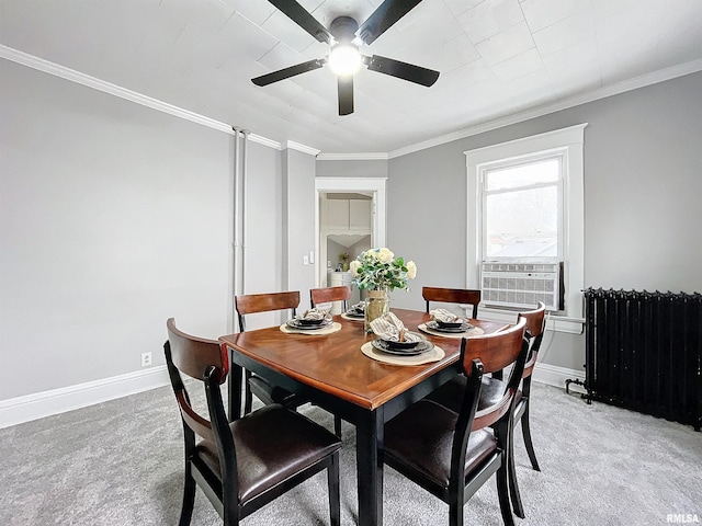 carpeted dining space with ceiling fan, radiator heating unit, and crown molding