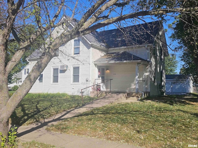 view of front of home featuring a wall mounted air conditioner, a front yard, and an outbuilding