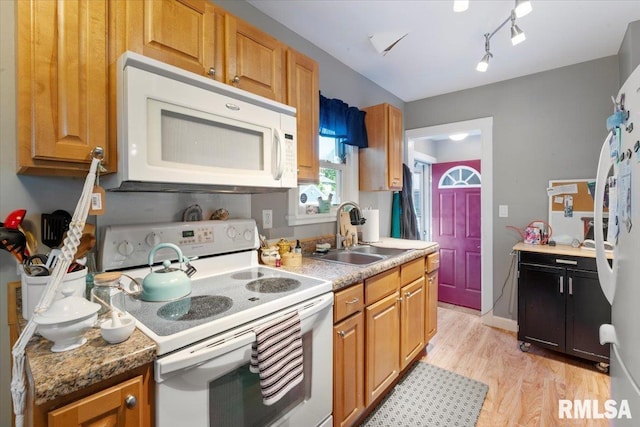 kitchen featuring dark stone countertops, white appliances, sink, and light hardwood / wood-style flooring