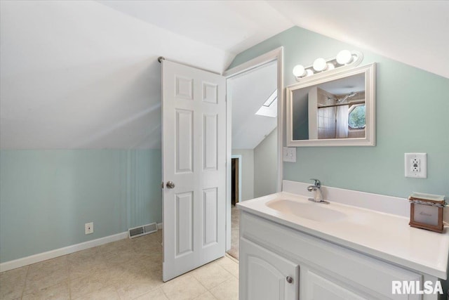 bathroom featuring lofted ceiling with skylight and vanity