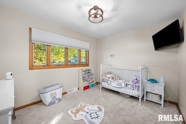 carpeted bedroom featuring a nursery area