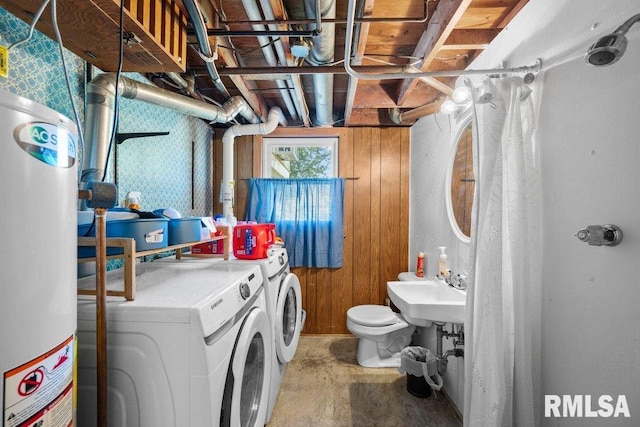 washroom with washer and dryer, sink, water heater, and wooden walls