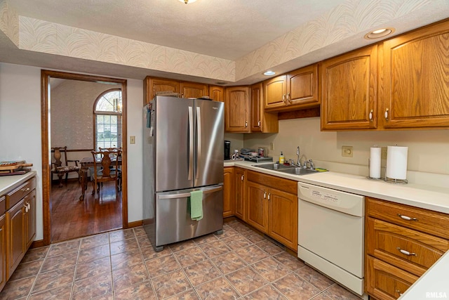 kitchen with a textured ceiling, white dishwasher, stainless steel refrigerator, dark wood-type flooring, and sink