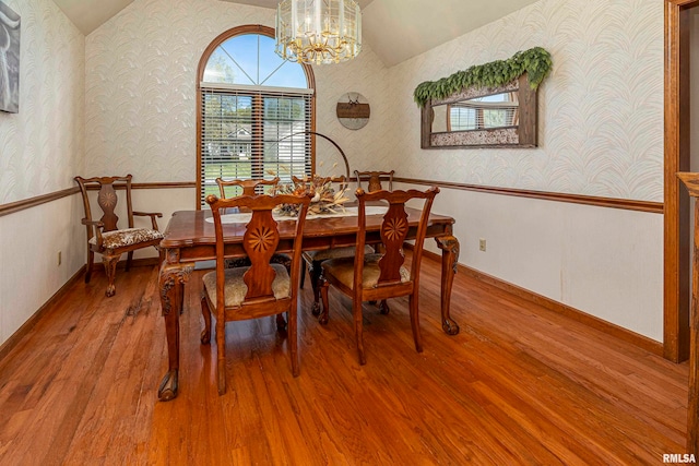 dining area with vaulted ceiling, an inviting chandelier, and hardwood / wood-style floors