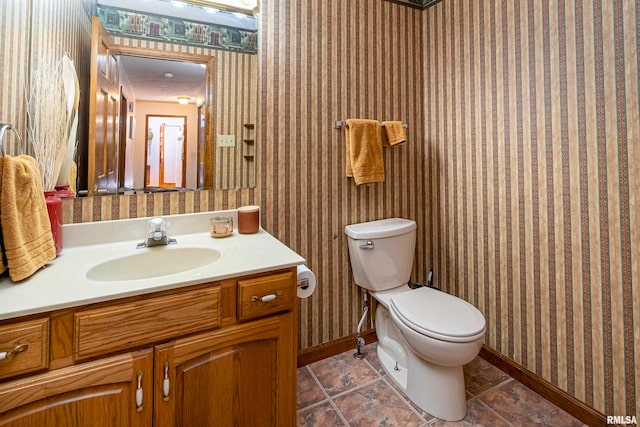 bathroom with toilet, vanity, and tile patterned flooring