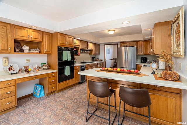 kitchen featuring kitchen peninsula, stainless steel fridge, a kitchen breakfast bar, gas cooktop, and double oven