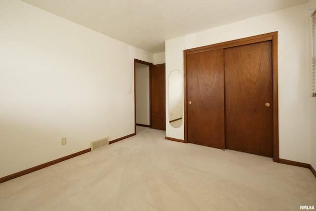 unfurnished bedroom featuring light carpet and a closet