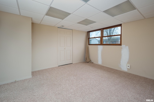 carpeted empty room with a drop ceiling