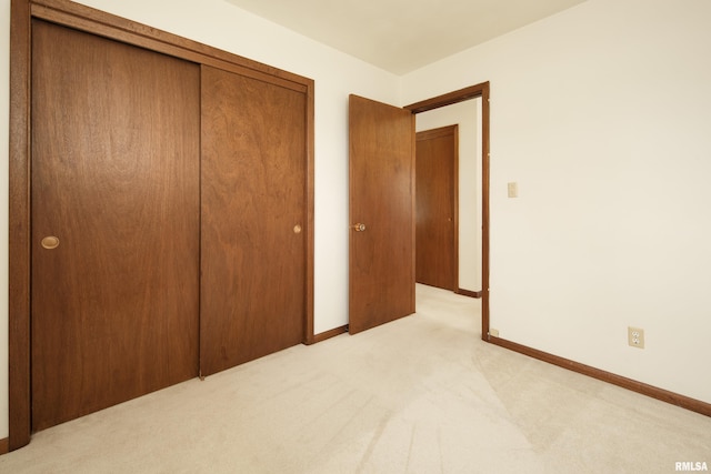 unfurnished bedroom featuring light colored carpet and a closet