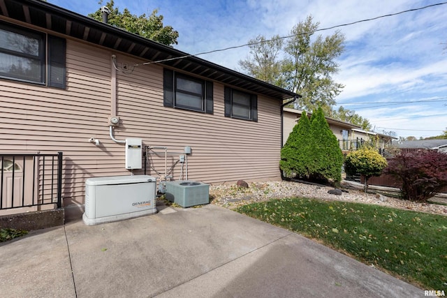 view of side of property with a lawn, cooling unit, and a patio