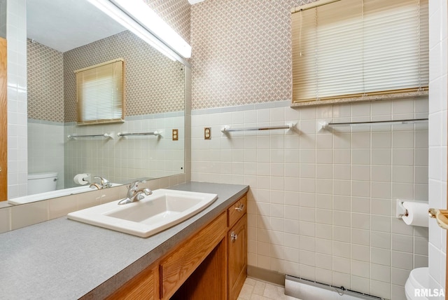 bathroom featuring toilet, a baseboard heating unit, vanity, and tile walls