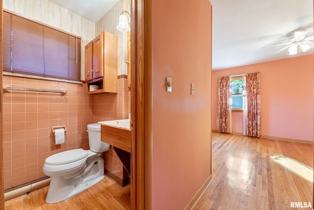 bathroom with toilet, wood-type flooring, tile walls, and ceiling fan