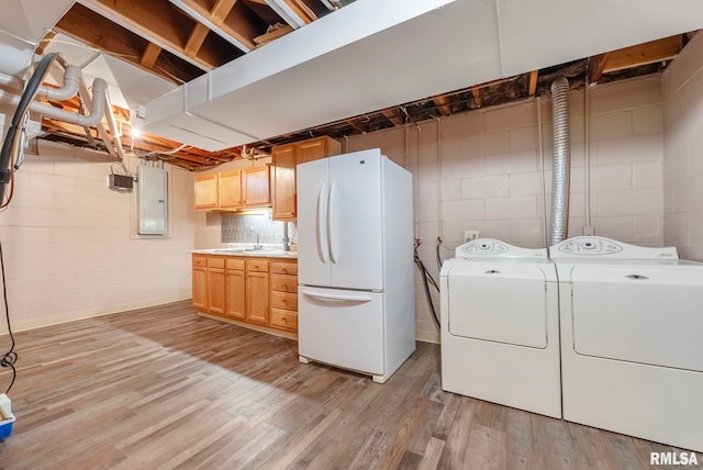 laundry room featuring sink, washer and dryer, electric panel, and light wood-type flooring