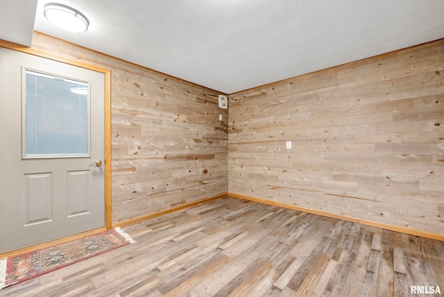 unfurnished room with wood walls and light hardwood / wood-style flooring