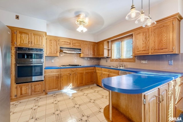 kitchen with tasteful backsplash, appliances with stainless steel finishes, sink, and hanging light fixtures