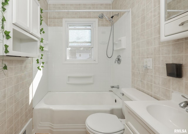 full bathroom with tile walls, vanity, tiled shower / bath, and toilet