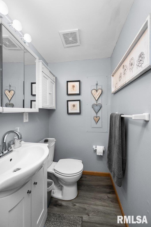 bathroom featuring vanity, wood-type flooring, and toilet