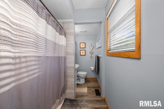 bathroom with toilet, hardwood / wood-style floors, and a shower with curtain