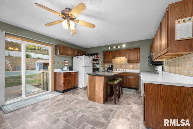 kitchen featuring backsplash, a center island, stove, white fridge, and a breakfast bar