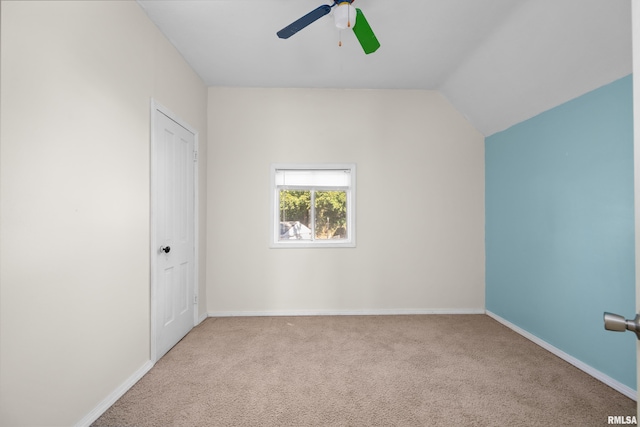 empty room featuring vaulted ceiling, light colored carpet, and ceiling fan