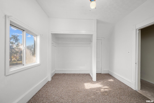 unfurnished bedroom with a closet, carpet, and vaulted ceiling