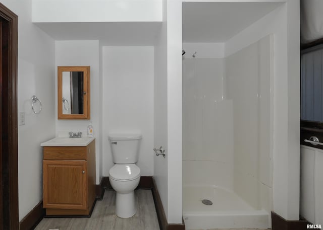 bathroom featuring hardwood / wood-style floors, vanity, a shower, and toilet