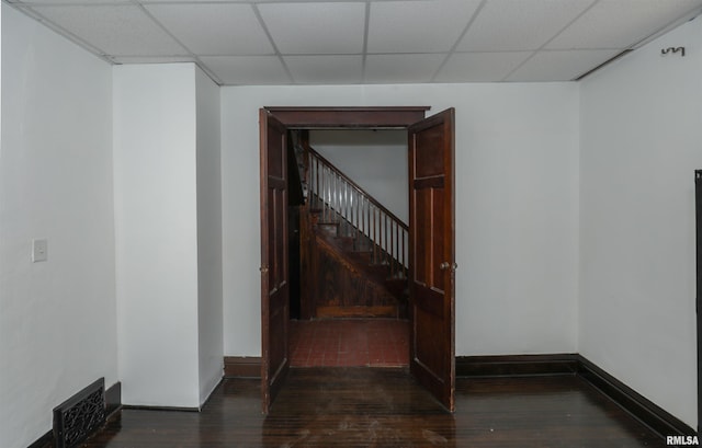 corridor with a drop ceiling and dark wood-type flooring