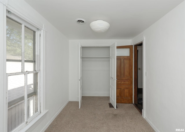 unfurnished bedroom featuring a closet and light carpet