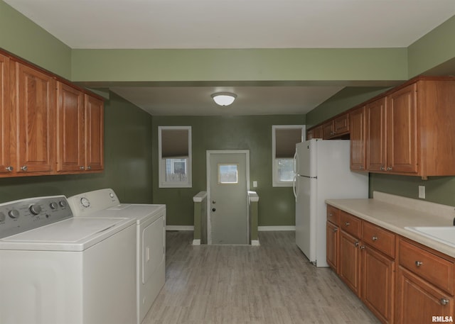 laundry area with sink, washing machine and dryer, and light hardwood / wood-style flooring