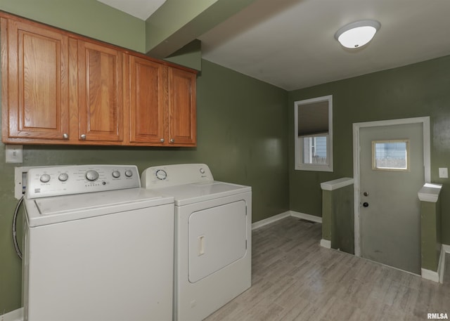 laundry area featuring light hardwood / wood-style floors, washer and dryer, and cabinets