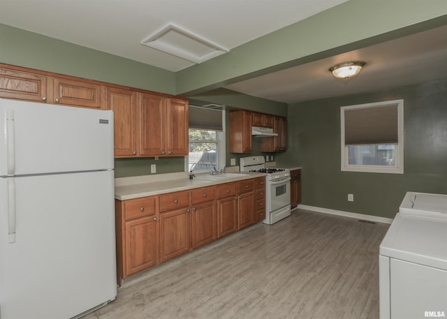 kitchen featuring light hardwood / wood-style floors, independent washer and dryer, sink, and white appliances