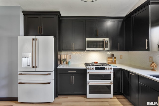 kitchen with light wood-type flooring, stainless steel appliances, and backsplash