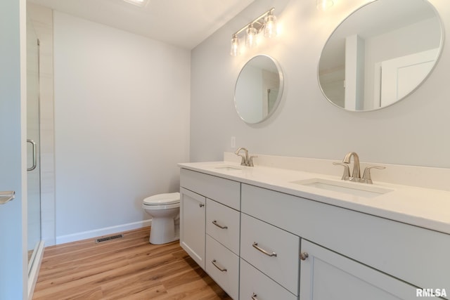 941 9th Ave N, Clinton, IA 52732 - full bathroom featuring double vanity, wood finished floors, and a shower with shower door