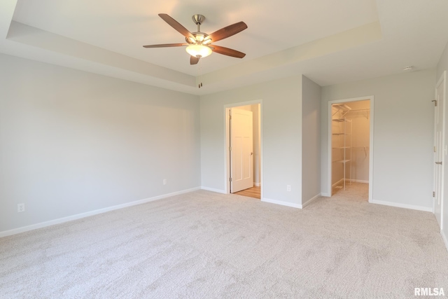 941 9th Ave N, Clinton, IA 52732 - unfurnished bedroom with a walk in closet, light colored carpet, a raised ceiling, a closet, and ceiling fan