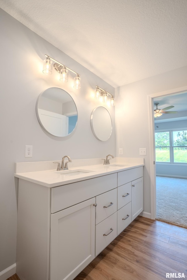 941 9th Ave N, Clinton, IA 52732 - full bath featuring double vanity, wood finished floors, a ceiling fan, and a textured ceiling