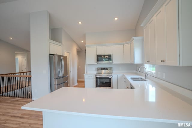 941 9th Ave N, Clinton, IA 52732 - kitchen featuring appliances with stainless steel finishes, light wood-type flooring, light countertops, a peninsula, and white cabinets