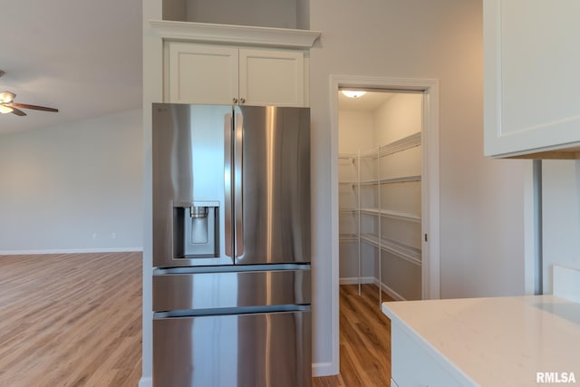 941 9th Ave N, Clinton, IA 52732 - kitchen with stainless steel refrigerator with ice dispenser, light wood-style flooring, a ceiling fan, and white cabinets
