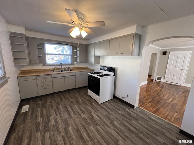 kitchen featuring gray cabinetry, dark hardwood / wood-style floors, sink, gas range gas stove, and ceiling fan