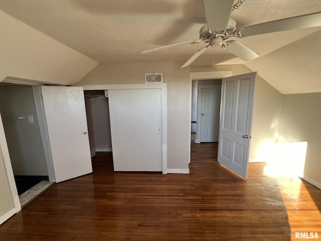 unfurnished bedroom with ceiling fan, lofted ceiling, a textured ceiling, and dark hardwood / wood-style floors