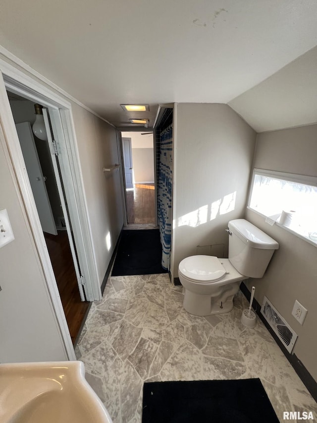 bathroom with hardwood / wood-style floors, toilet, lofted ceiling, and sink