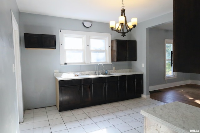 kitchen with light hardwood / wood-style flooring, sink, pendant lighting, and an inviting chandelier