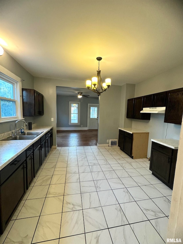 kitchen featuring a healthy amount of sunlight, sink, hanging light fixtures, and ceiling fan with notable chandelier