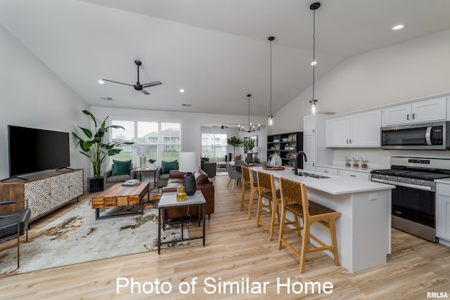 kitchen featuring appliances with stainless steel finishes, sink, an island with sink, white cabinetry, and light hardwood / wood-style flooring